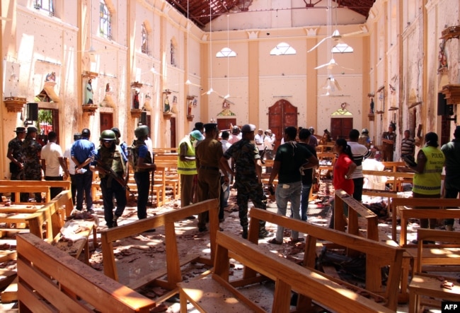Sri Lankan security personnel walk through debris following an explosion in St Sebastian's Church in Negombo, north of the capital Colombo, on April 21, 2019.