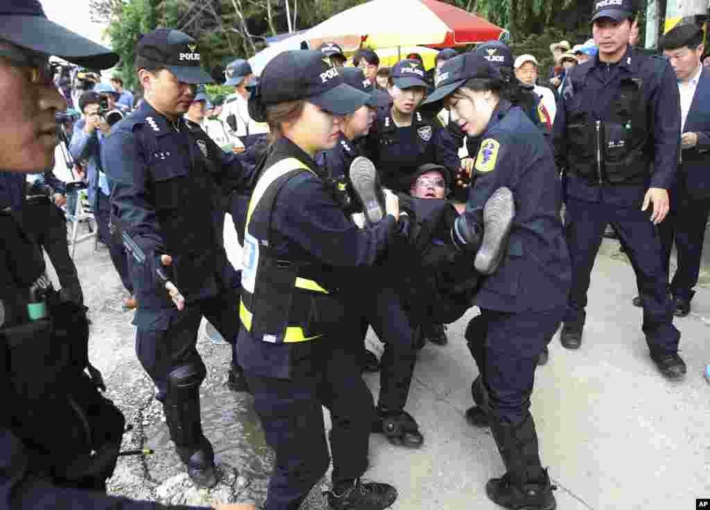 Police officers separate a Buddhist believer from Evangelical Baptist Church believers as she denounced them near the main gate of the church in Anseong, South Korea, Wednesday, June 11, 2014.