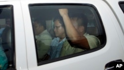 Ny Chakrya, center, former ADHOC and a National Election Committee member who worked at the organization, sits in a car and is transported back to an Anti-Corruption Unit, ACU, after a short appearance at Phnom Penh Municipal Court, in Phnom Penh, Cambodia, Saturday, April 30, 2016. Cambodian authorities arrested five human rights workers last Friday on accusations they tried to help cover up a woman's affair with the deputy leader of the opposition Cambodia National Rescue Party. The action is the latest in a series by Prime Minister Hun Sen's government putting legal pressure on its critics and political opponents. (AP Photo/Heng Sinith)