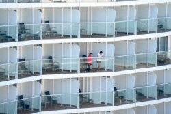 Passengers look out from the Spectrum of the Seas cruise ship docked at Kai Tak cruise terminal in Hong Kong, Jan. 5, 2022.