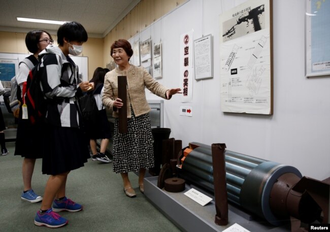 FILE - Haruyo Nihei explains to school girls visiting a museum about the March 10, 1945, U.S. firebombing in Tokyo, Japan, April 19, 2019.