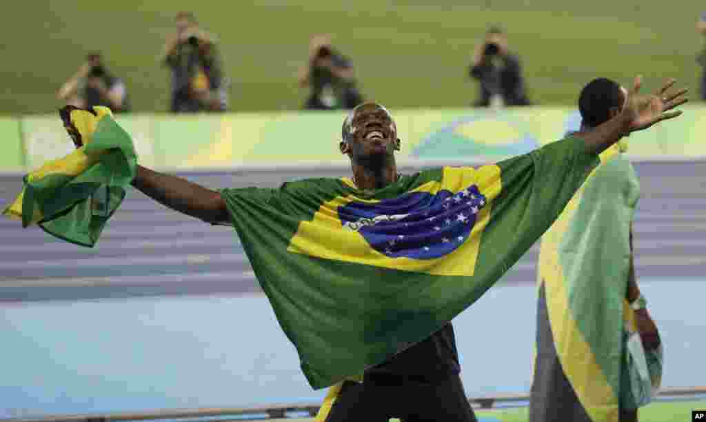 Usain Bolt de la Jamaïque bras étendus, couvert du drapeau brésilien et tenant le drapeau de son pays en main, célèbre après avoir remporté la médaille d&#39;or en finale du 4x100 mètres relais messieurs lors des compétitions d&#39;athlétisme des Jeux Olympiques d&#39;été de 2016 au stade olympique de Rio de Janeiro, au Brésil, 19 août 2016.