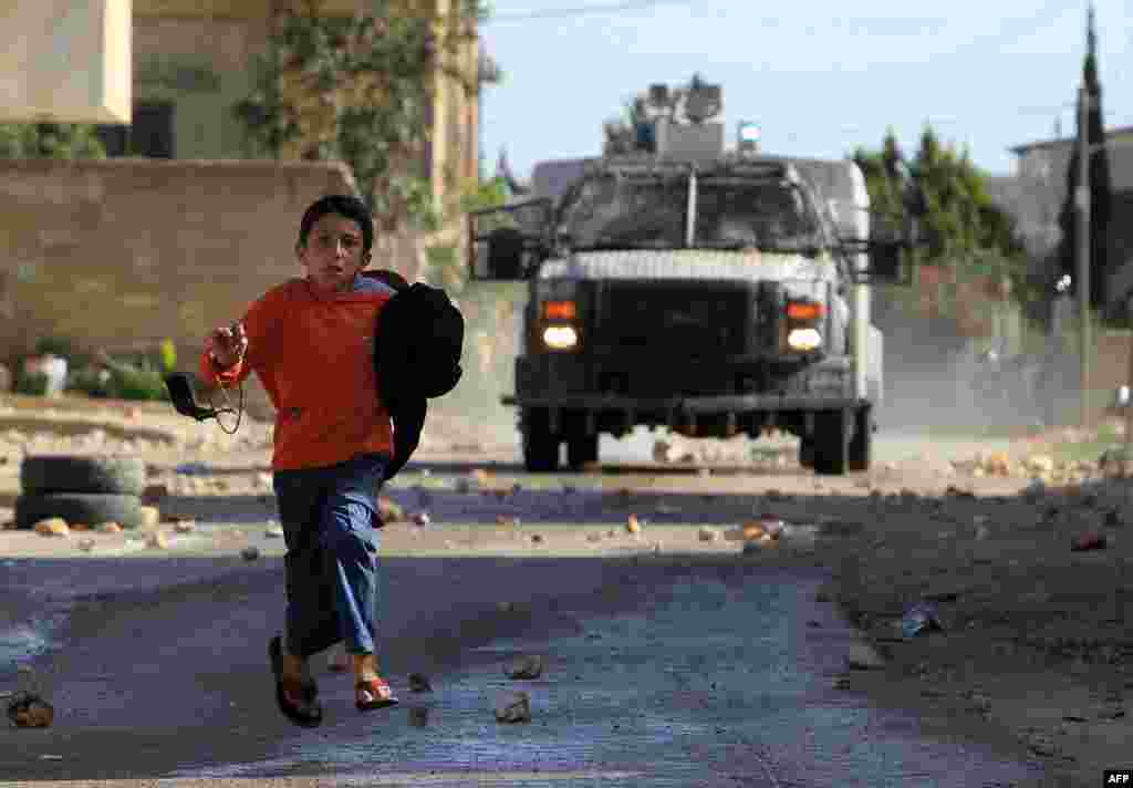 A Palestinian protester runs for cover as an Israeli military vehicle sprays a foul-smelling spray known as "skunk" during clashes following a demonstration against the expropriation of Palestinian land by Israel in the village of Kfar Qaddum, near Nablus in the occupied West Bank.