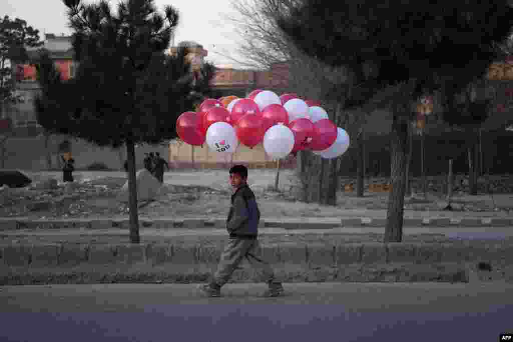 An Afghan child walks with balloons he is selling on a street in Kabul.