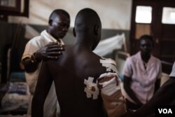 A medical officer at the hospital in Aba, Democratic Republic of Congo, cares for Isaac Bida, 22, who was shot in the back amid fighting in South Sudan, on Dec. 19, 2017.