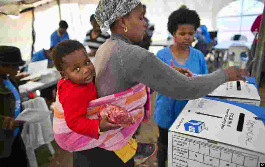 A mother casts her vote at a polling station in the Alexandra township of Johannesburg, South Africa, May 7, 2014.
