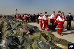 Rescue workers carry the body of a victim of a Ukrainian plane crash in Shahedshahr, southwest of the capital Tehran, Iran, Wednesday, Jan. 8, 2020.