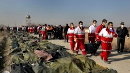 Rescue workers carry the body of a victim of a Ukrainian plane crash in Shahedshahr, southwest of the capital Tehran, Iran, Wednesday, Jan. 8, 2020.