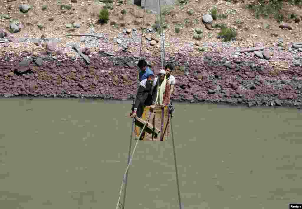 People cross the Chenab river on a trolley tied to wires to cast their vote at Harshi village in Doda district, north of Jammu, India.