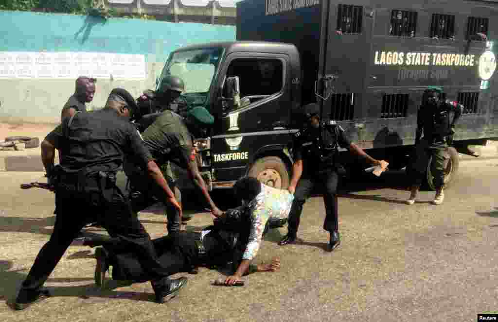 Police officers pull a journalist during an anti-government protest in Lagos, Nigeria.