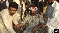 A man injured by a bombing in Dera Ghazi Khan is helped by local residents, 15 Dec 2009