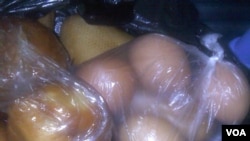 In Douala, Cameroon, a consumer purchases eggs and bread distributed in plastic bags. (VOA / D. Ntaryike)