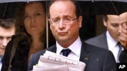 French President Francois Hollande holds newspapers accompanied by his companion Valerie Trierweiler, left, in Tulle, June 10, 2012.