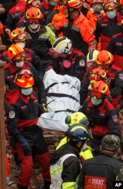 Rescuers carry a victim recovered from a collapsed building following a strong earthquake in Hualien County, eastern Taiwan, Feb. 8, 2018. A magnitude 6.4 earthquake struck late Tuesday night caused several buildings to cave in and tilt dangerously.