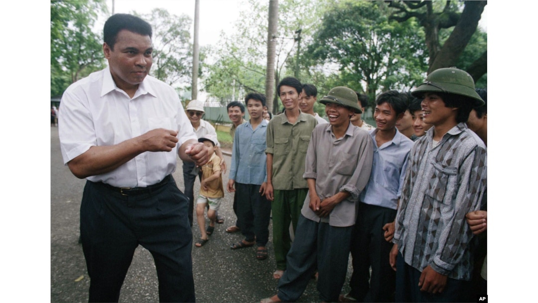 FILE - Muhammad Ali, left, assumes his former fighting stance while joking around with Vietnamese people on the path outside of Ho Chi Minh's former home in Hanoi, Vietnam, May 11, 1994. Ali visited the families of American and Vietnamese servicemen still missing from the war, nearly three decades after he was convicted of draft evasion for refusing to fight on the battlefields.
