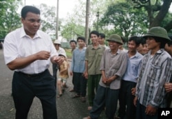 FILE - Muhammad Ali, left, assumes his former fighting stance while joking around with Vietnamese people on the path outside of Ho Chi Minh's former home in Hanoi, Vietnam, May 11, 1994. Ali visited the families of American and Vietnamese servicemen still missing from the war, nearly three decades after he was convicted of draft evasion for refusing to fight on the battlefields.