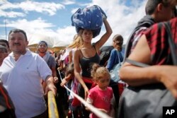 FILE - A woman carrying a bundle on her head waits in line to cross the border into Colombia through the Simon Bolivar International Bridge in San Antonio del Tachira, Venezuela, July 17, 2016.