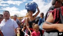 FILE - A woman carrying a bundle on her head waits in line to cross the border into Colombia through the Simon Bolivar International Bridge in San Antonio del Tachira, Venezuela, July 17, 2016.