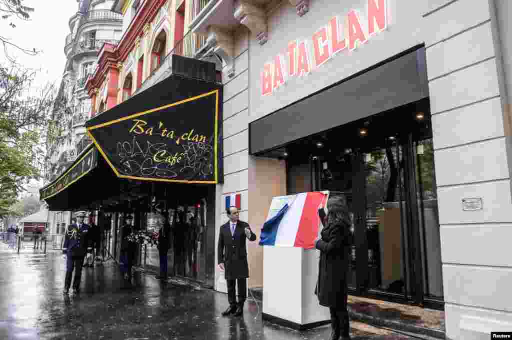 Presiden Perancis Francois Hollande dan Walikota Paris Anne Hidalgo menyibak penutup plakat di depan gedung konser Bataclan di Paris (13/11) upacara untuk mengenang para korban serangan maut di Paris tahun lalu yang menewaskan 130 orang. (Reuters/Christophe Petit Tesson)