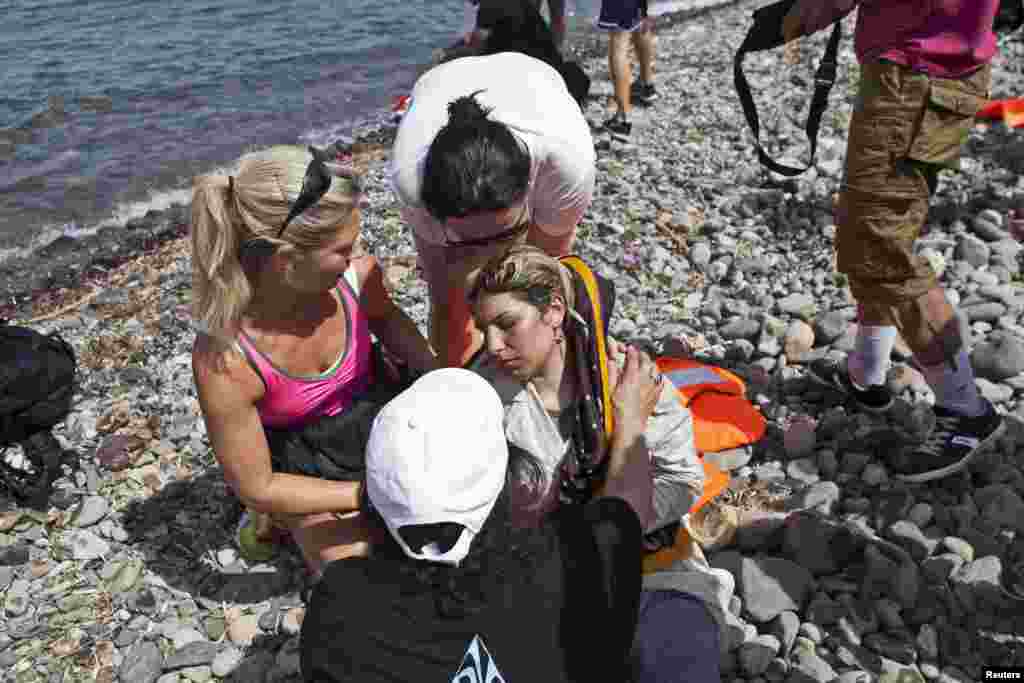 Volunteers help a Syrian refugee (C) who collapsed moments after arriving on a dinghy on the Greek island of Lesbos, Sept. 7, 2015.