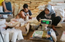 Penjual gula mengemas gula dalam kemasan yang lebih kecil sebelum dijual ke pelanggan di Tangerang, Banten pada 3 April 2020. (Foto: AFP/Fajrin Rahardjo)
