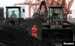 FILE - An employee walks between front-end loaders, which are used to move coal imported from North Korea at Dandong port in the Chinese border city of Dandong, Liaoning province Dec. 7, 2010.