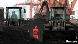 FILE - An employee walks between front-end loaders, which are used to move coal imported from North Korea at Dandong port in the Chinese border city of Dandong, Liaoning province Dec. 7, 2010.