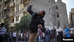 A protester throws stones at riot police during clashes at Tahrir square in Cairo November 26, 2012.