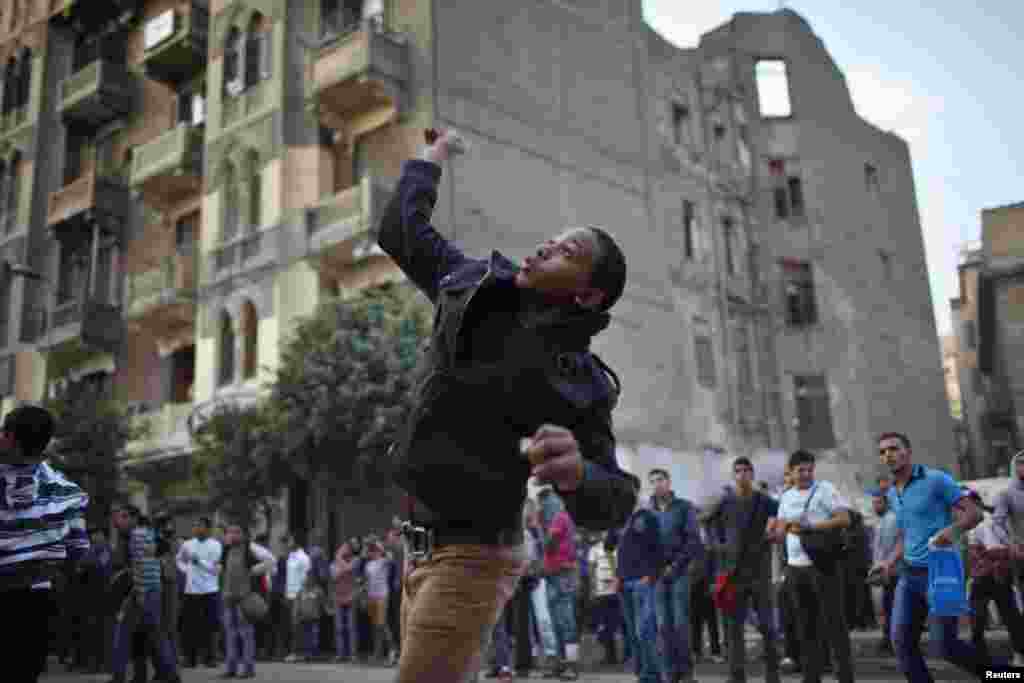 A protester throws stones at riot police during clashes at Tahrir square in Cairo November 26, 2012.