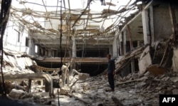 A man stands amidst the rubble on Dec. 17, 2018, at a factory damaged during fighting and air strikes.