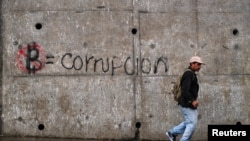 Un hombre pasa por un graffiti que dice "Bitcoin es igual a corrupción", que es parte de una campaña contra el uso del bitcóin como moneda de curso legal, en San Salvador, El Salvador, el 5 de octubre de 2021.