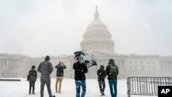 来自法国的游客欣赏冬季风暴给美国首都华盛顿带来的雪景。(2022年1月3日)