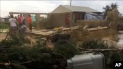 In this image made from a video, people stand near a house damaged by Tropical Cyclone Gita in Nuku’alofa, Tonga, Feb. 13, 2018.
