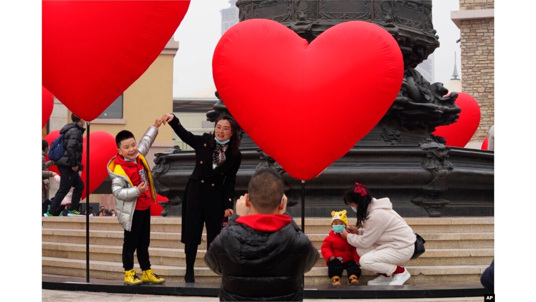 FILE - Families with young children pose for photos in Beijing, Feb. 13, 2021. Struggling with an aging population and a declining birth rate, China is trying to shift its population policies to avert a demographic crisis.