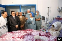 In this photo released 28 Dec 2010 by the Tunisian President's office, Tunisia's President Zine El Abidine Ben Ali, 2nd left, visits Mohamed Bouazizi, a young man who set himself on fire after police confiscated fruit and vegetables he sold without a perm