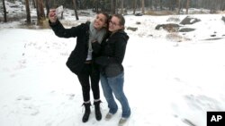 Emily, left, and her sister Stephanie pose for a selfie in the snow at a rest stop, Nov. 3, 2017, at Donner Summit, Calif. A light snow fell in the upper elevations of the Sierra Nevada overnight, with up to 2 feet of snow forecast in elevations above 8,000 feet and at least a foot of snow is expected in areas above 6,000 feet.