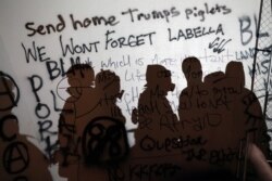 TThe silhouette of demonstrators is seen against a wall covered in graffiti during a protest against racial inequality in front of the federal courthouse in Portland, Oregon, U.S. July 17, 2020.