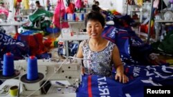 A worker poses for pictures as she makes flags for U.S. President Donald Trump's "Keep America Great!" 2020 re-election campaign at Jiahao flag factory in Fuyang, Anhui province, China, July 24, 2018.