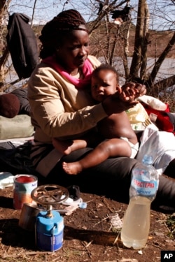 FILE - Sandrine Koffi washes her 10-months-old daughter Kendra with river water during a rest near the village of Marvintsi, Macedonia, March 3, 2015.