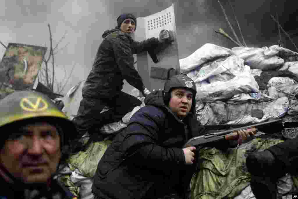 An anti-government protester holds a firearm as he mans a barricade on the outskirts of Independence Square in Kiev, Ukraine, Thursday, Feb. 20, 2014. Fierce clashes between police and protesters, some including gunfire, shattered a brief truce in Ukraine