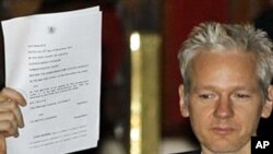 WikiLeaks founder Julian Assange holds up a court document for the media after he was released on bail, outside the High Court, London, 16 Dec 2010