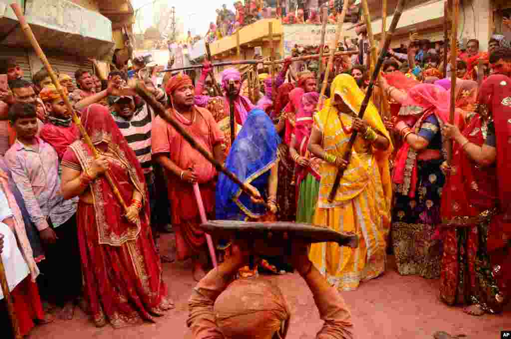 Indian women from Barsana village beat a villager from Nandgoan with wooden sticks as he teases them during Lathmar holi festival celebrations at the legendary hometown of Radha, consort of Hindu god Krishna, in Barsana.