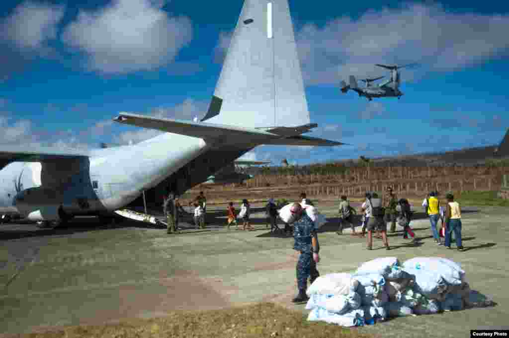 Philippine citizens board an HC-130 Hercules as U.S. sailors transport relief supplies in support of Operation Damayan. (U.S. Navy)