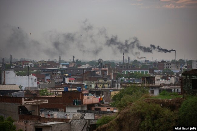 FILE - Smoke rises from chimneys of leather tanneries in Kanpur, an industrial city on the banks of the river Ganges, India, Tuesday, June 23, 2020. (AP Photo/Altaf Qadri)