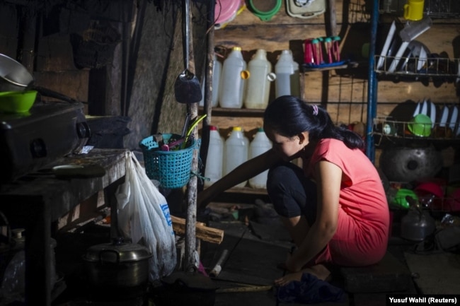 Seorang gadis yang menikah di bawah umur pada Maret 2020, sedang memasak di dapurnya di Botteng Utara di Mamuju, Sulawesi Barat. (Foto: AFP/Yusuf Wahil)