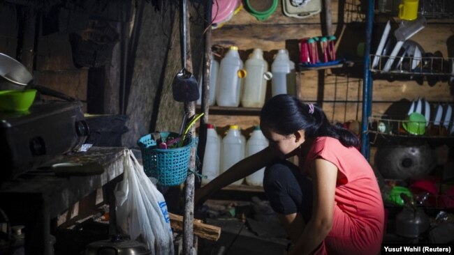 Seorang gadis yang menikah di bawah umur pada Maret 2020, sedang memasak di dapur rumahnya di Botteng Utara di Mamuju, Sulawesi Barat, pada 24 Juli 2020. (Foto: AFP/Yusuf Wahil)