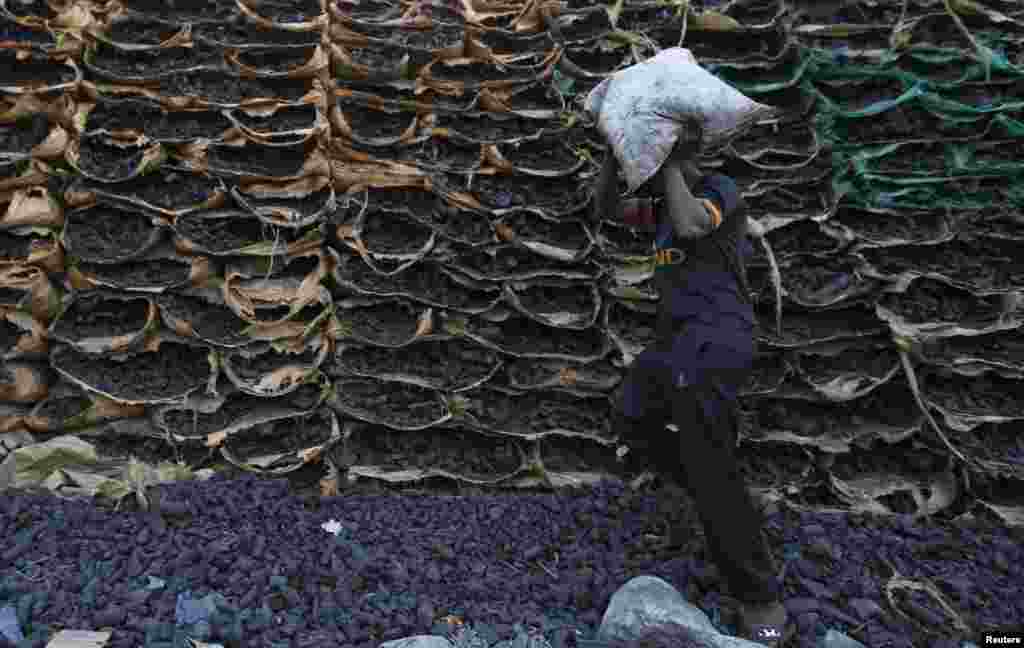 A worker carries a bag containing coals to sell at one of the charcoal sites in Jeddah, Saudi Arabia.