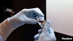  A lab technician visually inspects a filled vial of investigational coronavirus disease (COVID-19) treatment drug remdesivir at a Gilead Sciences facility in La Verne, California, U.S. March 11, 2020. 