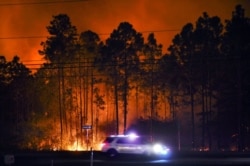 Kendaraan sherif terlihat melintas di sepanjang Highway 98 di Walton County, Florida, saat terjadi kebakaran, Rabu malam, 6 Mei 2020.