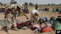 FILE- Soldiers guard people fleeing from Boko Haram’s carnage, Dec. 8, 2015. People detained by the military and a civilian self-defense force are disappearing in northeast Nigeria some wrongly accused of fighting for Boko Haram.
